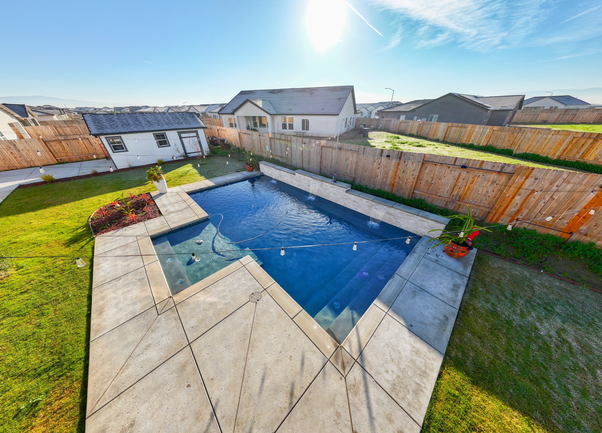 Aerial view of custom gunite pool with dark plaster and wide concrete deck